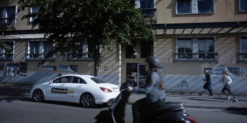 A traveler runs down the street with a woman.