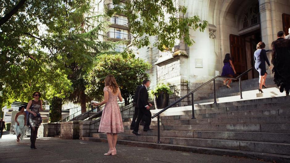 A very hungover Alex walks up to Kara who is waiting out front of the church.