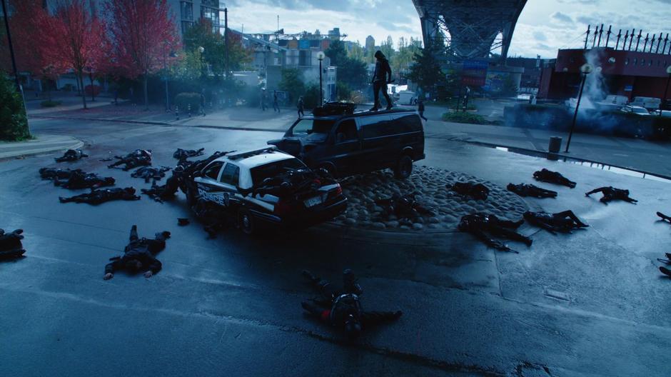 Oliver stands on top of a van after killing his evil doppelgänger while surrounded by dead soldiers.