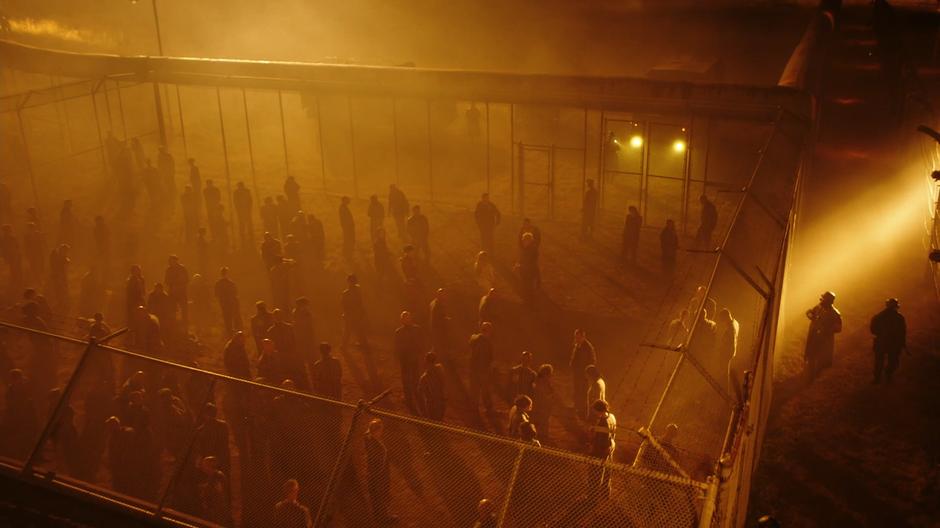 Prisoners mill around inside the fenced in area.