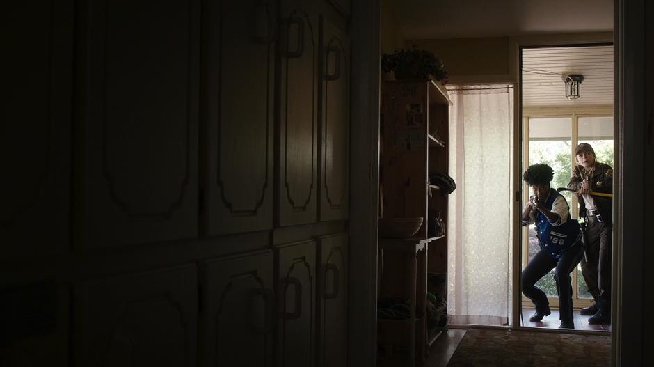 Farah and Tina look down the hallway after breaking into the house.