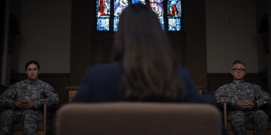 Grace sits in front looking at the members of the tribunal.