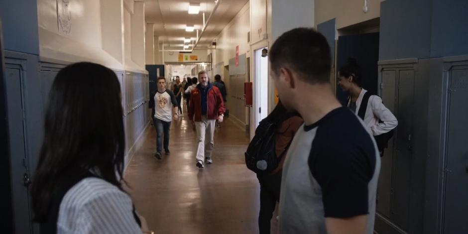 Grace and Trevor turn as Coach Perry approaches them in the hallway.