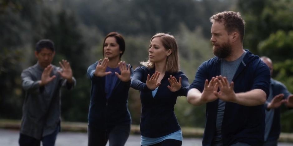 Marcy and David practice yoga with several other people.