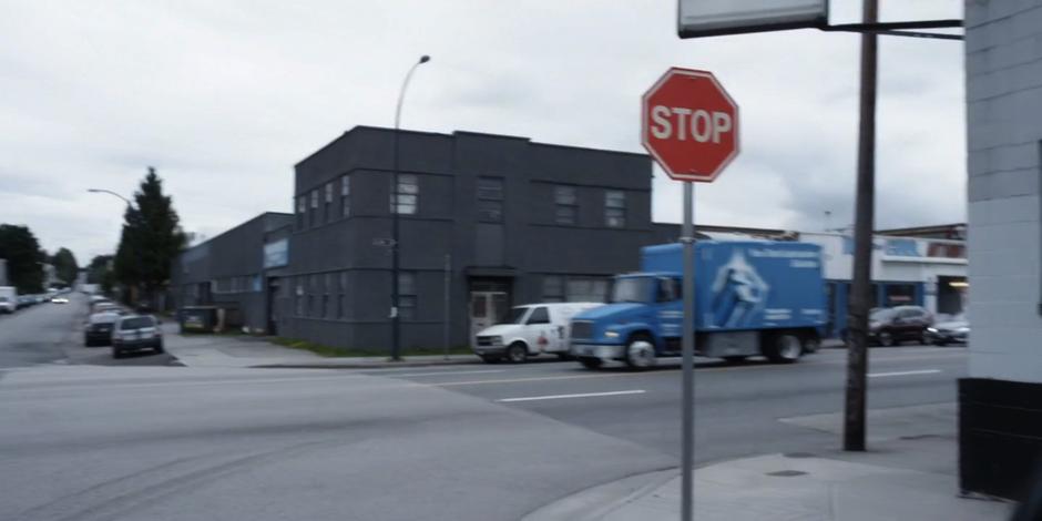 A truck drives through the intersection that Kyle is stopped at.