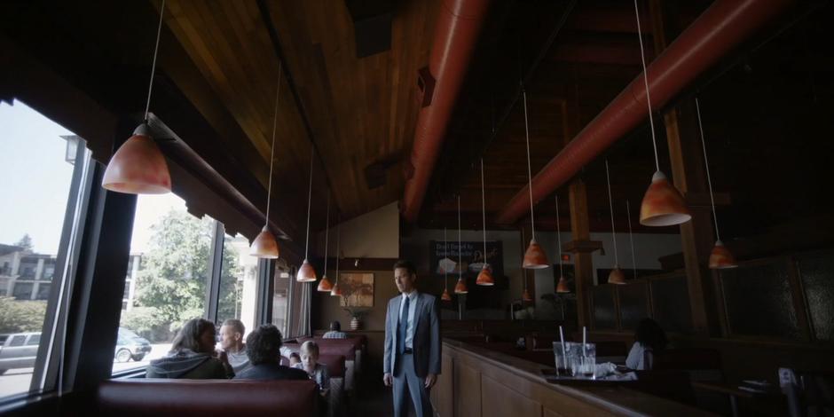 Grant walks up to the table where Rick, Luca, Kyle, and Anna are sitting.