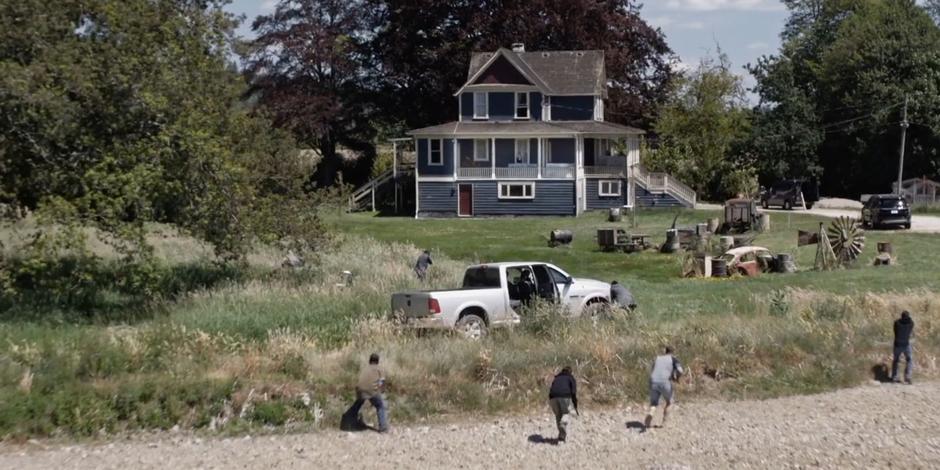 The Faction agents rush to the house and take cover behind their truck and in the tall grass.