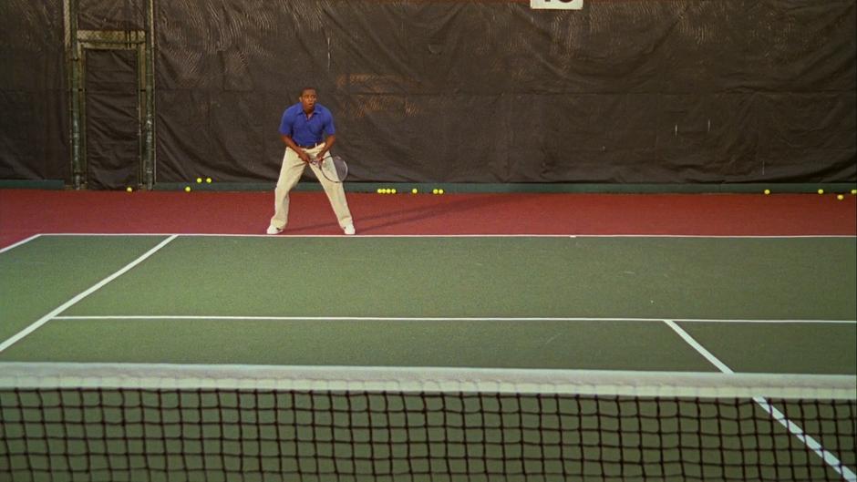 Gus takes up a position on the opposite end of the tennis court.