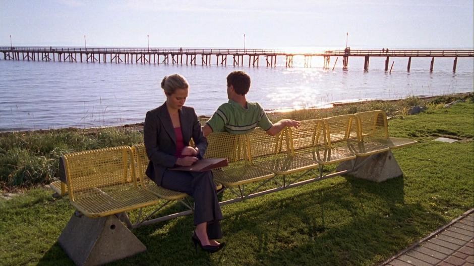 Shawn sits down on the opposite side of the bench from where Juliet is waiting.