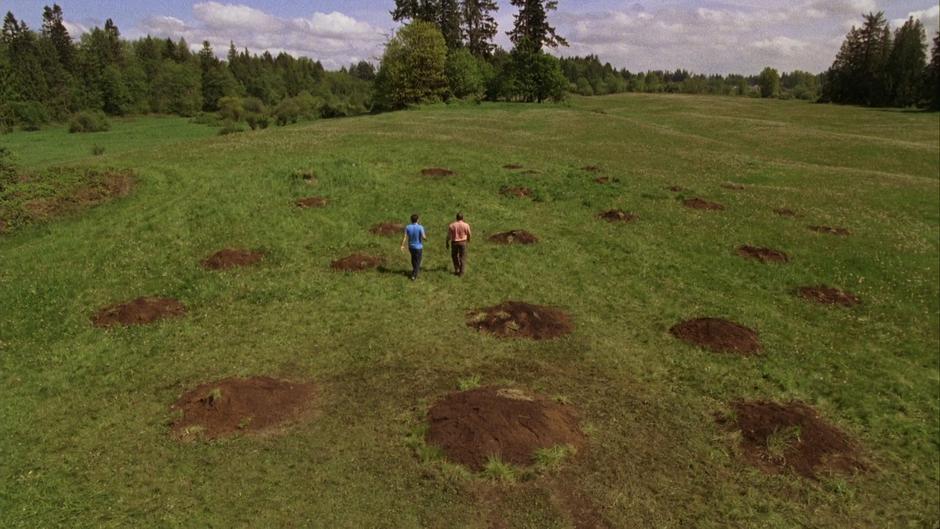 Shawn and Gus walk through the middle of the field of holes.