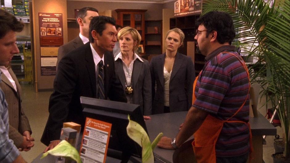 Ewing interrogates the store clerk who accepted the counterfeit bills while everyone else stands around.