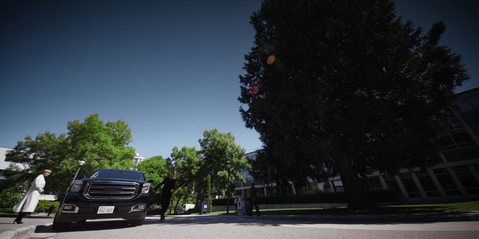 A guard walks around the car to open the door for Dr. Perrow.