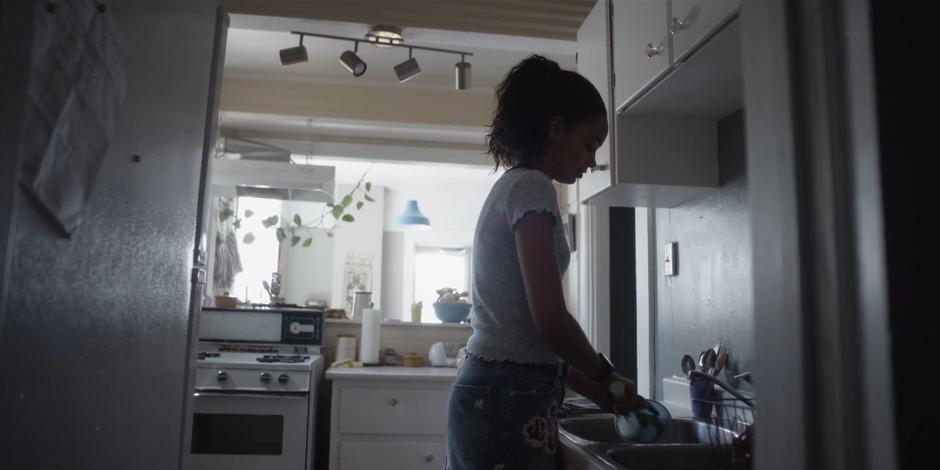 Carly washes dishes in the sink in the morning.