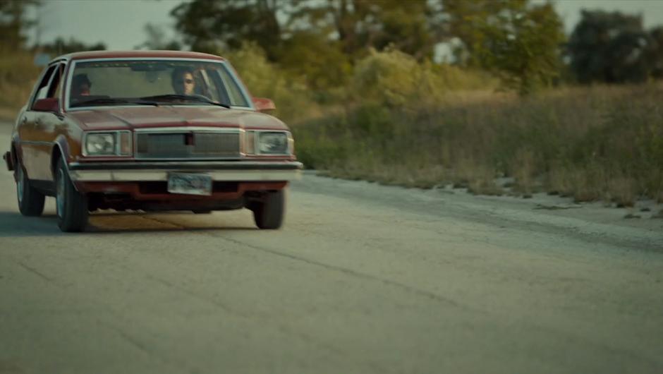 A man drives a blindfolded Mary down the street.