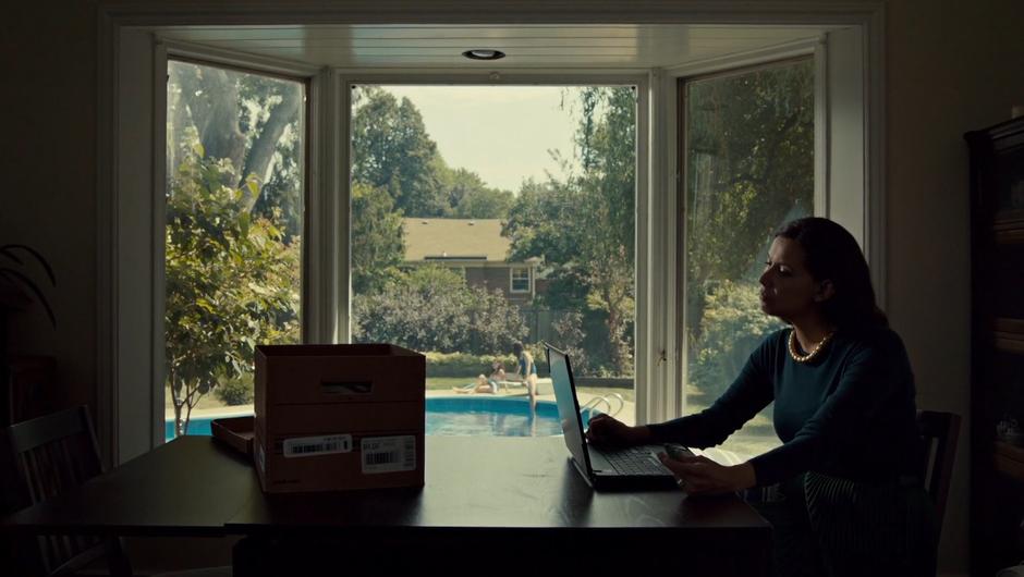 Louise watches footage of Mary on her computer while Jess and Naomi play in the backyard.