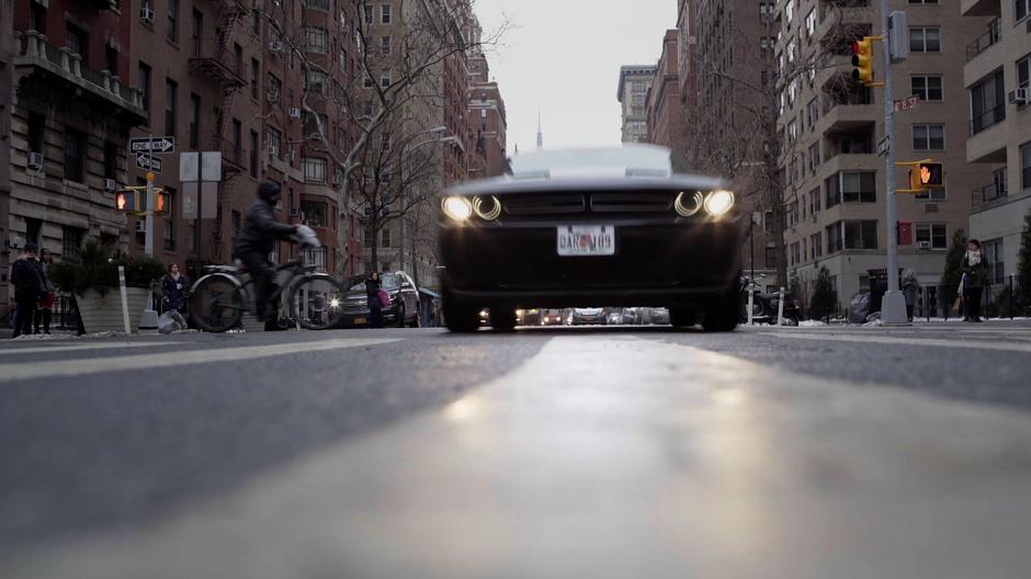 Lenny Cohen drives down the street towards the camera.