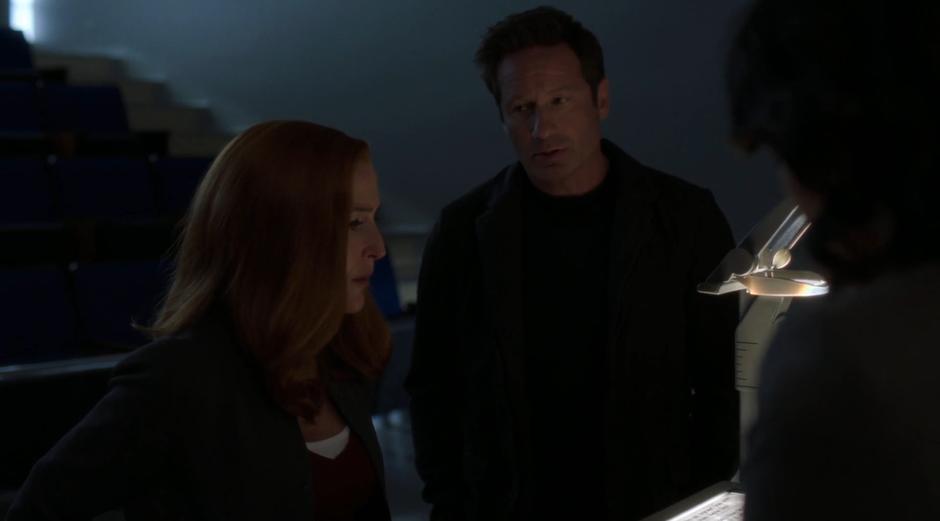 Scully and Mulder approach Karah Hamby after her class with the chip they found at the grave.
