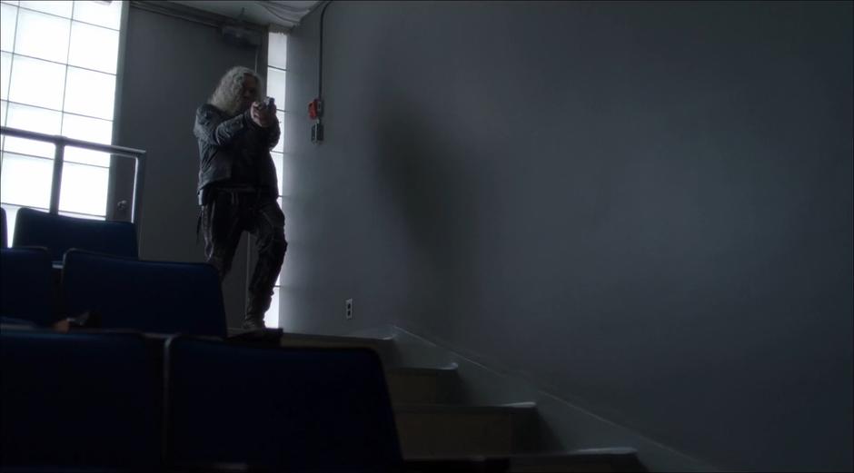 The white-haired mercenary fires at Karah Hamby from the top of the lecture hall.