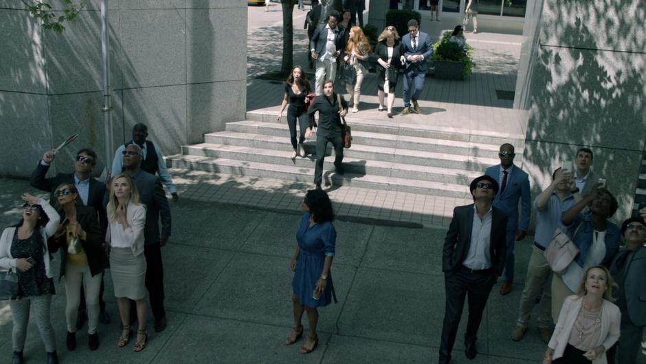 Julia and Quentin run towards the building as a crowd gathers.