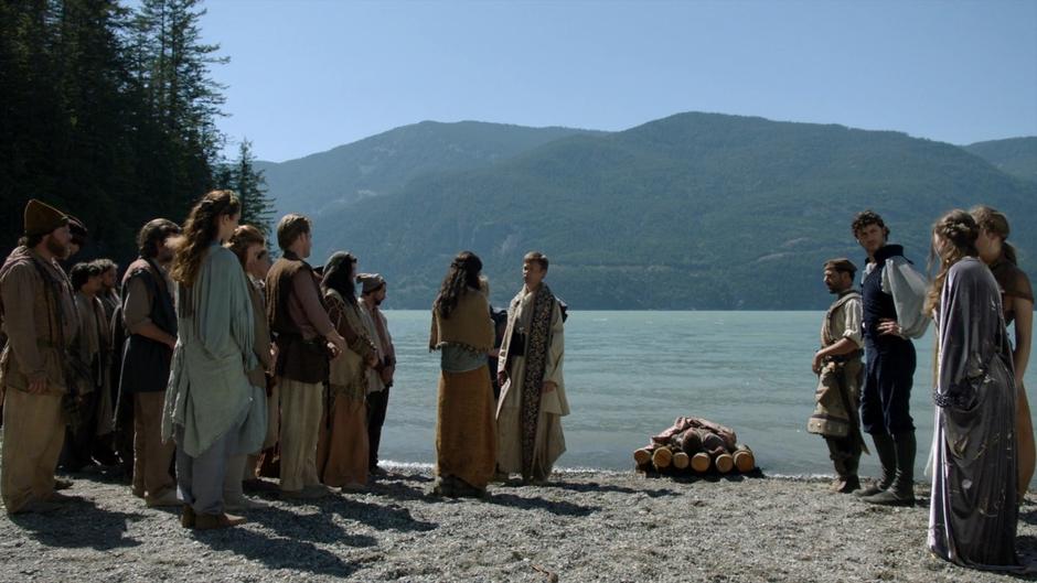 Father Poe talks to Shara at her husband's funeral while Eliot, Fray, and Fen stand off to the side.