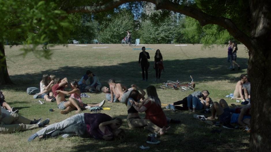 Quentin and Julia walk up to a big group of people kissing and stripping on the lawn.