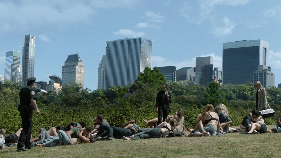 Quentin and Alice look over as a police officer orders the people to break it up.