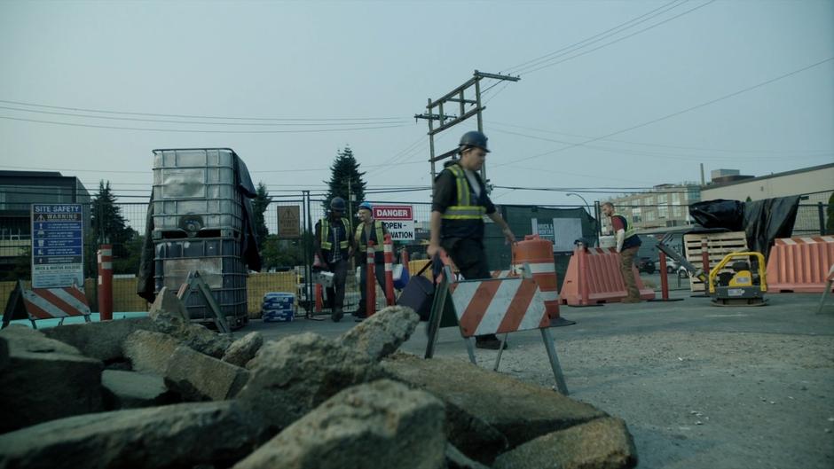 Several of the construction workers head off to lunch while one remains behind.