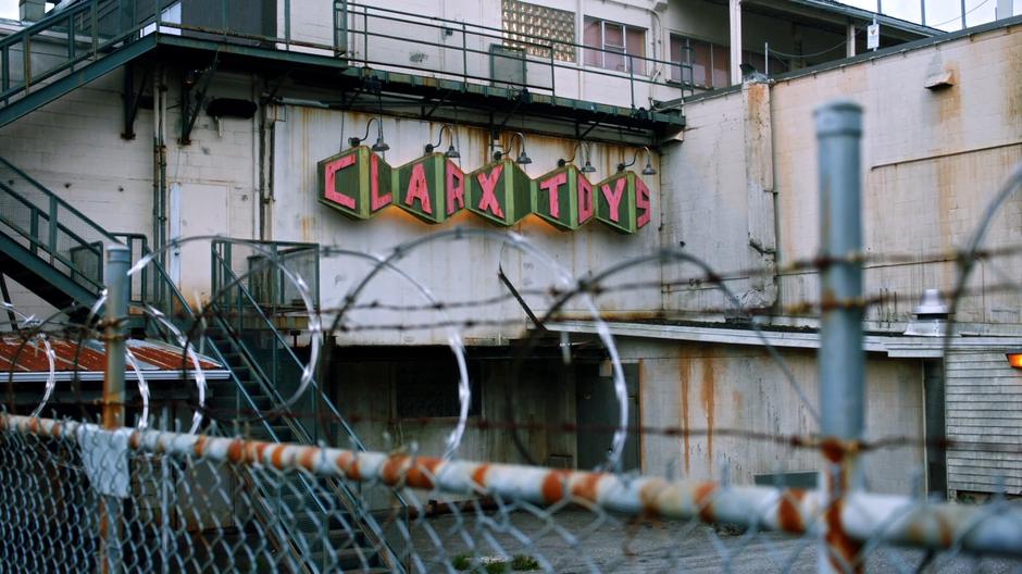 Establishing shot of the delapitated Clarx Toys sign on the outside of the factory.