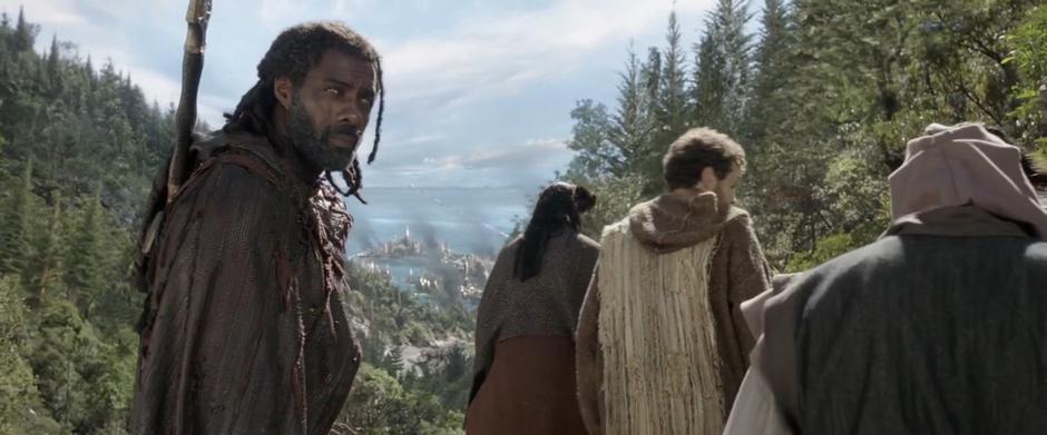 Heimdall looks back up the mountain while a line of refugees head down towards the burning city.