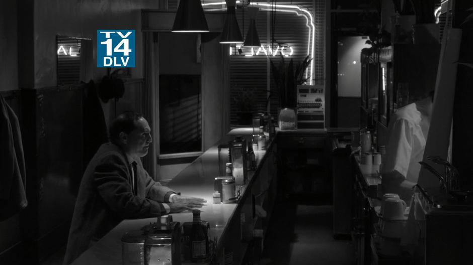 A nervous man sits at the bar in the diner.