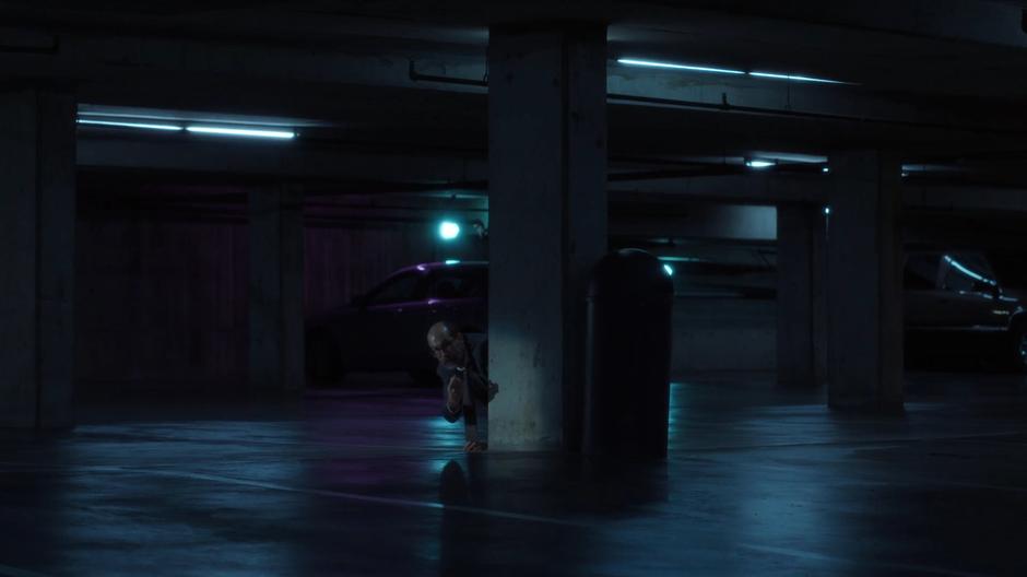 Reggie tries to get Mulder and Scully's attention while crouched behind a pillar.