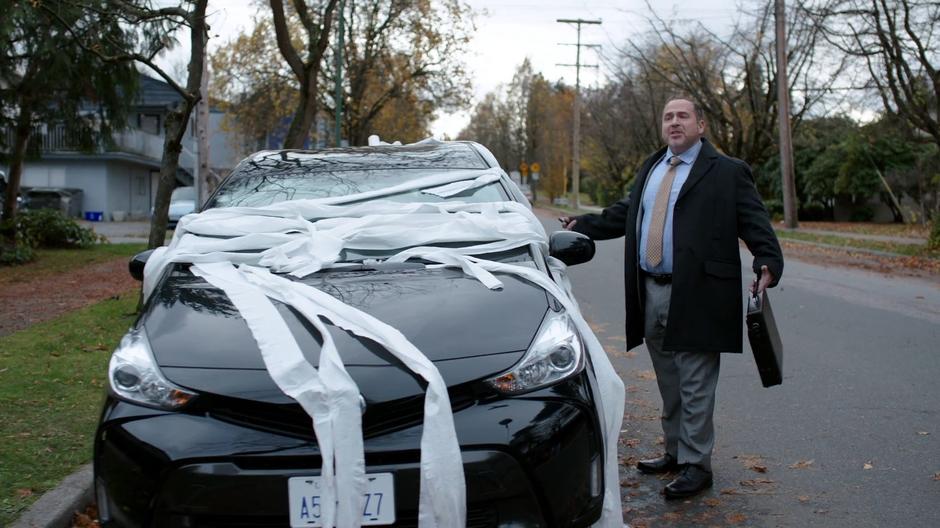 Councilman Grovner looks around in front of his toilet paper covered car.