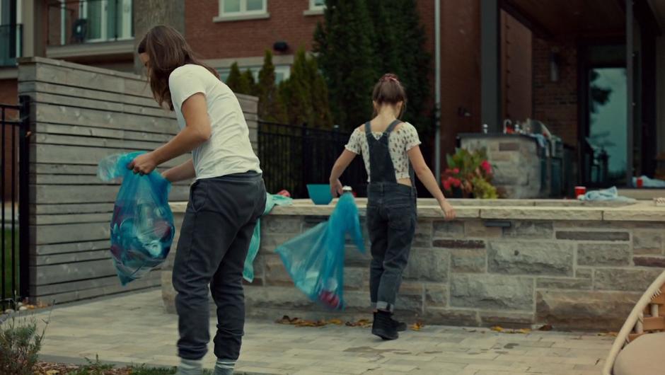 Jess and Naomi pick up trash in the back yard.