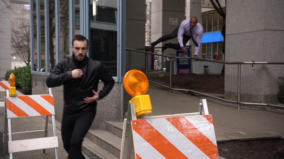 James hops over a railing while chasing after the assassin.