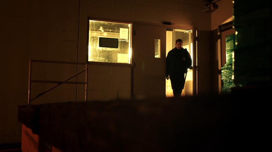 A security guard walks out of the door onto the loading dock.