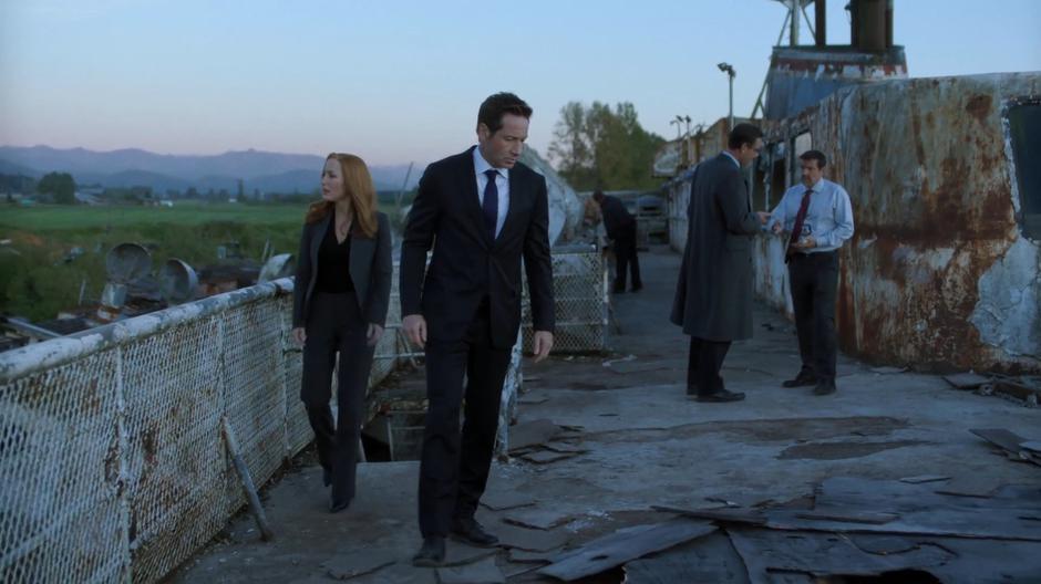 Scully and Mulder walk onto the upper deck of the old ship.