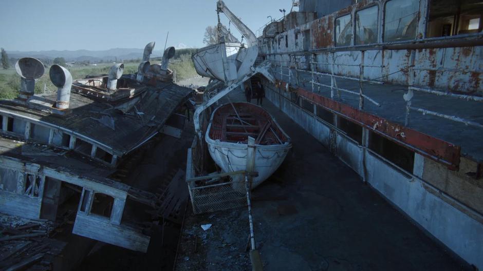 Scully and Mulder walk along the side of the decaying ship.