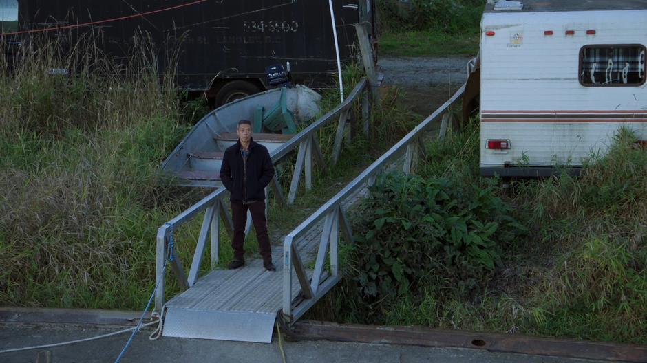 Peter Wong stands on the ramp leading from shore looking up at Scully.