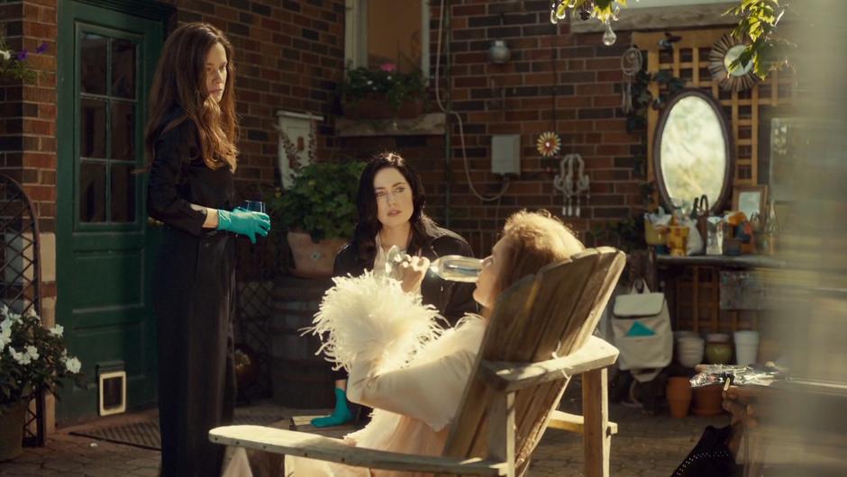 Mary and Nicole watch as Estelle drinks down the final drink.