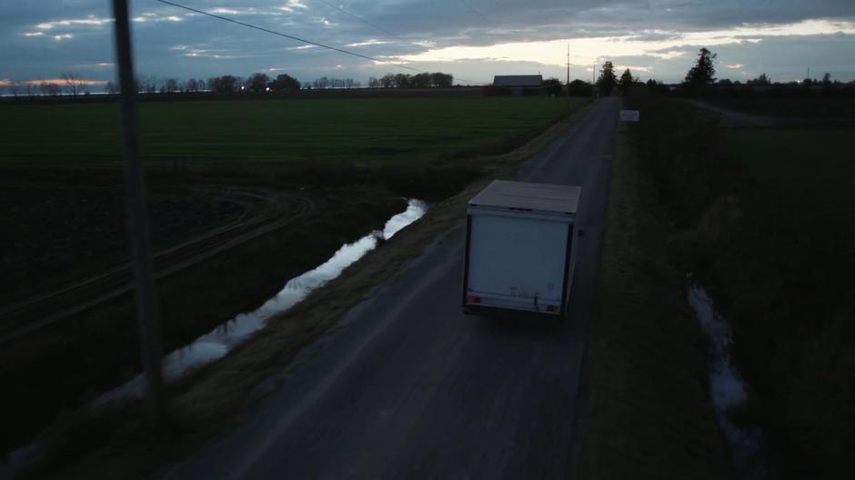 An unmarked truck drives down the street towards town.