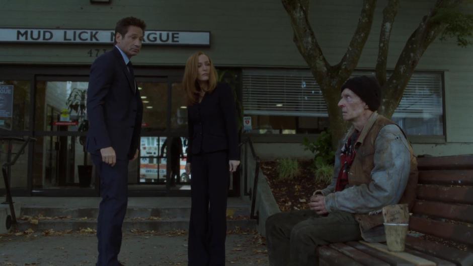 Mulder and Scully turn around as a homeless man says something to them.