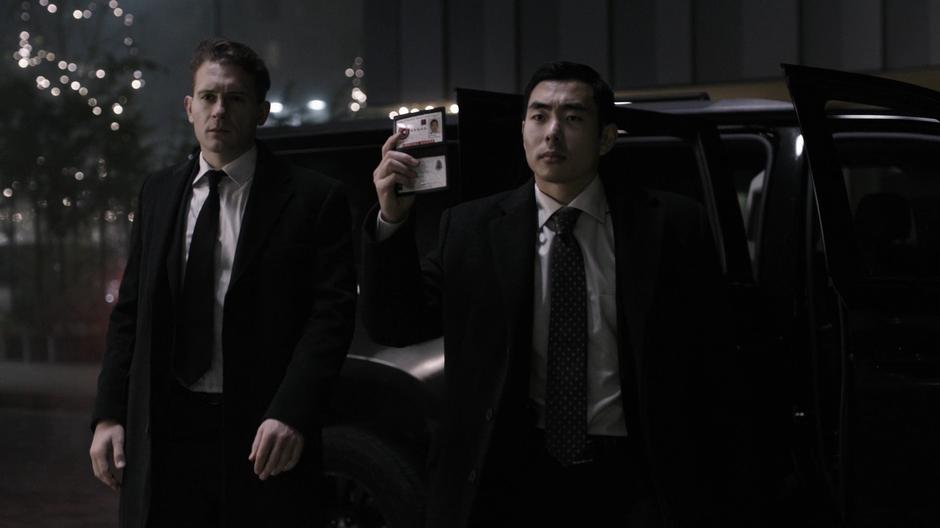A pair of A.R.G.U.S. agents approach Cayden James while one of them shows his ID.