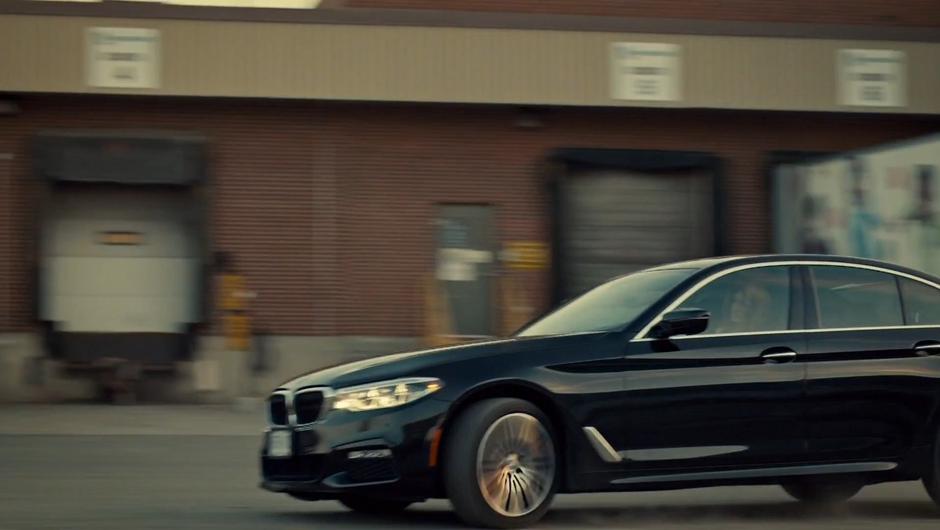 Olivia drives her car past a line of loading docks.