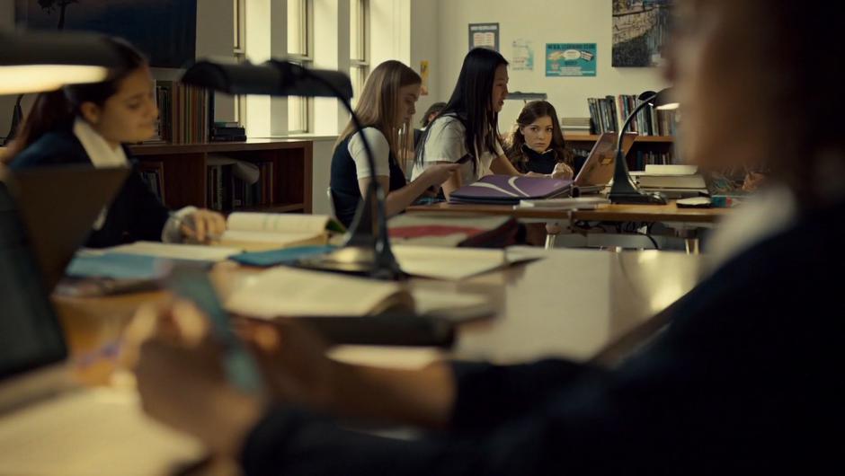 Naomi stares at Heather from across the classroom.