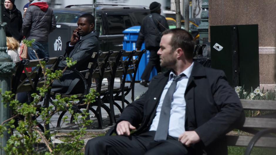 Reade and Weller sit on nearby benches looking around the park for their target.