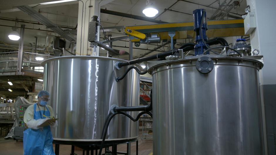 An employee walks past the grinding vats as a brain falls into one of them.