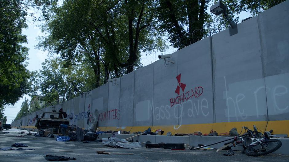 The wall covered with cameras and graffiti runs along the side of the park.