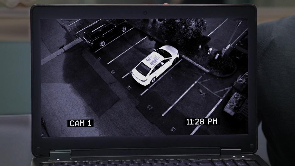 A white car with "Go Hawks" graffitied on the roof pulls into a parking spot on surveillance footage.