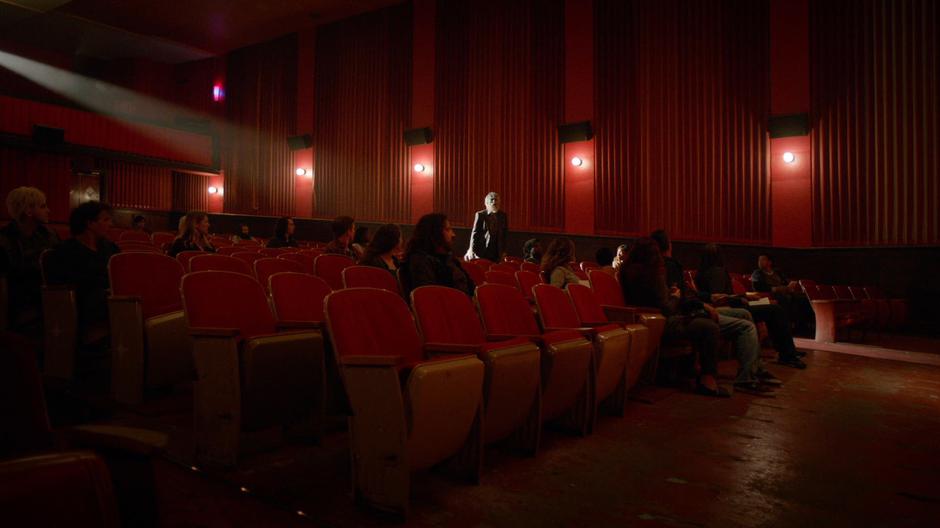 Angus calls out to the priest while walking down the aisle of the theater.