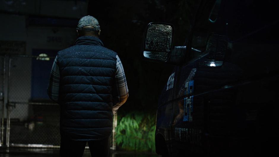 The delivery driver stands beside his van.